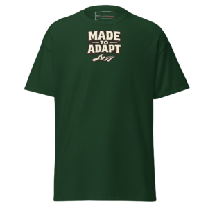 Front view of a forest-green T-Shirt featuring cream “Made To Adapt” lettering above a small field-and-tool motif